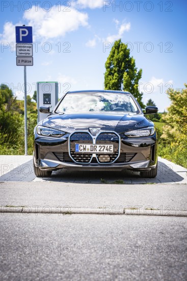 A black car is parked at a charging station with clear blue sky, BMW i7 electric car, Deer e-Carsharing, Calw, Germany