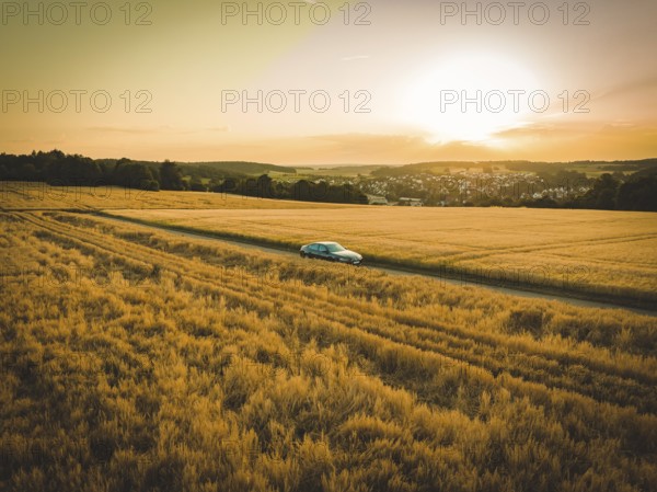 Car in the middle of vast fields at sunset with a view of the distant horizon, BMW i7 electric car, Deer e-Carsharing, Calw, Germany