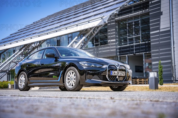 Black car next to a modern building with solar panels and clear sky, BMW i7 electric car, Deer e-Carsharing, Calw, Germany