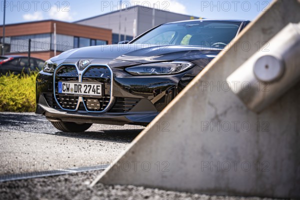 A modern black car in front of an industrial building in sunny weather, BMW i7 electric car, Deer e-Carsharing, Calw, Germany