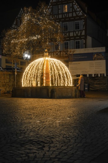 Atmospheric illuminated fountain at night in a paved old town scenario, Calw, Black Forest, Germany