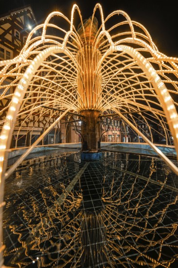 Artistic view of an illuminated fountain with detailed water reflections at night, Calw, Black Forest, Germany