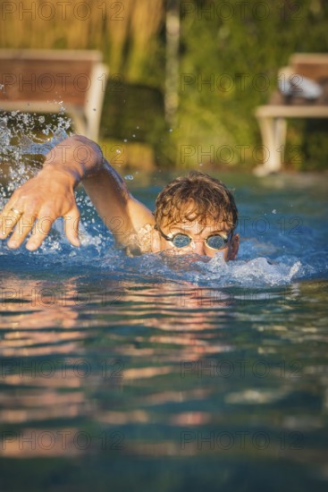 A man actively swims in the pool in sunshine and creates water splashes, Triathlon, Calw, Germany