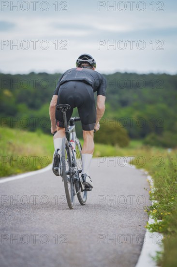 Cyclist in sporty clothes riding on a country road through green nature, Triathlon, Calw, Germany