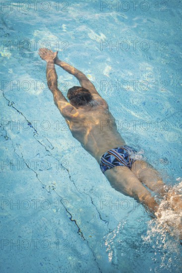 A diver in the pool shows dynamic underwater movements with splashing water, Triathlon, Calw, Germany