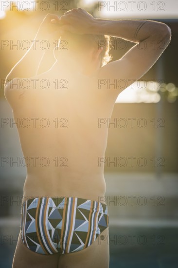Man wearing colorful swim trunks enjoying the sun at the edge of the pool, Triathlon, Calw, Germany