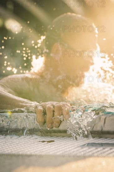 Close-up of a swimmer whose hand dynamically touches the water, light reflections, triathlon, Calw, Germany