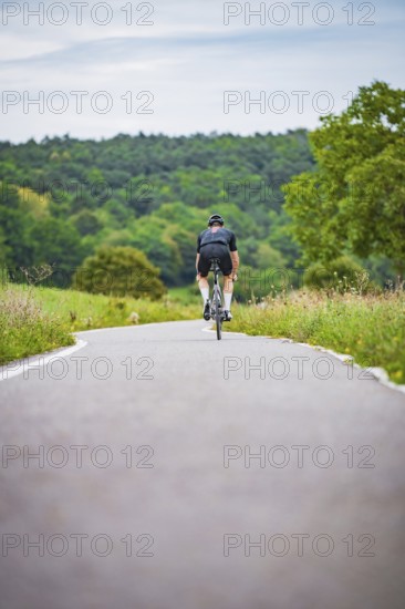 Cyclists in the distance on a winding country road surrounded by green countryside, Triathlon, Calw, Germany