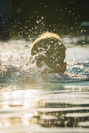A swimmer moves energetically through the water in sunlight, Triathlon, Calw, Germany