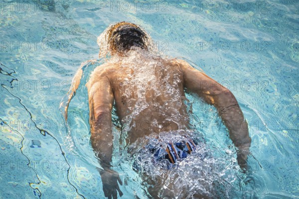 A swimmer in the pool shows energetic movements with strong splashes of water, Triathlon, Calw, Germany