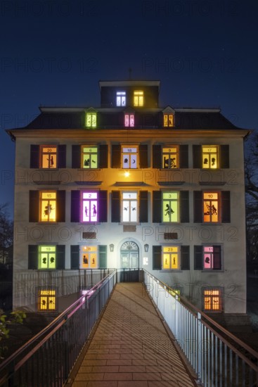 The windows of the Holzhausenschlösschen in Holzhausenpark in Frankfurt am Main shine brightly in December as Frankfurt's largest advent calendar. Each window shows an individual motif as a shadow cut, Holzhausenpark, Frankfurt am Main, Hesse, Germany