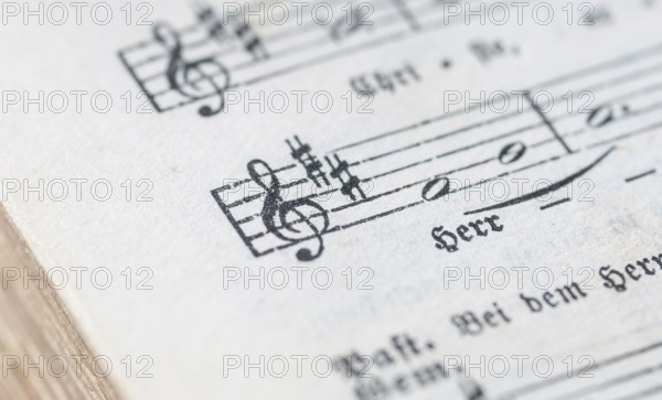 Close-up of a sheet music with musical symbols and text in black and white, historical, old, antique church hymnbook with religious song, score, notation, bar, beat, shift, sign, key, cross, semitone, whole notes, singing, worship, Lower Saxony, Germany