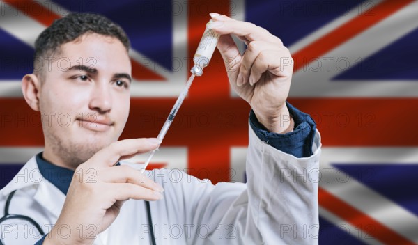 Doctor holding syringe on United Kingdom flag background. Medical professional holding syringe with British flag in the background