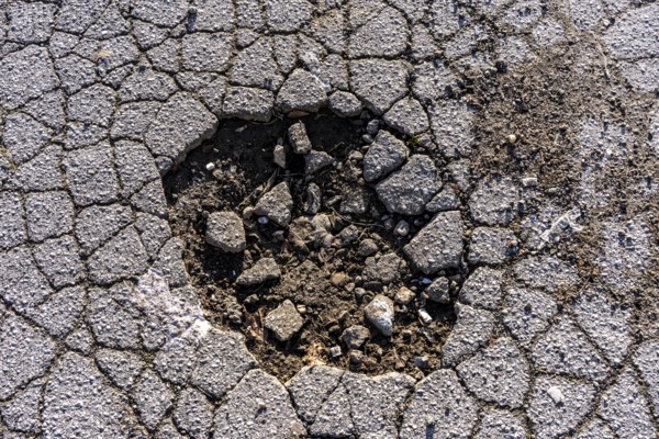 Pothole, asphalt surface, floor, with many small cracks, roadway, parking lot