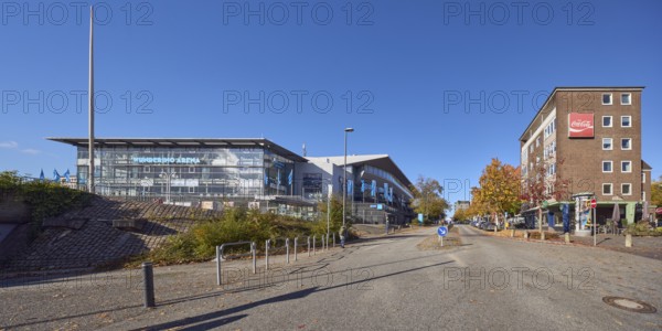 Wunderino Arena multi-purpose hall, general architecture, brick buildings, residential buildings and commercial buildings, advertising flags on flagpoles, advertising drink Coca-Cola, neon sign, lantern, barrier bollard, central island, traffic sign prescribed direction right past, blue sky, cloudless, Kleiner Kuhberg, Waisenhofstraße and Europaplatz intersection, Kiel, state capital, district-free city, Schleswig-Holstein, Germany