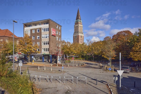 Residential and commercial buildings, brick buildings, brick architecture, general architecture, town hall tower, advertising drink Coca-Cola, barrier, central island, lantern, trees, autumn leaves, cyclists as a secondary motif, blue sky, cumulus clouds, roads intersection Kleiner Kuhberg with Waisenhofstraße, Kiel, state capital, district-free city, Schleswig-Holstein, Germany