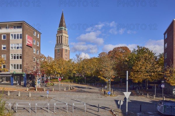 Residential and commercial buildings, brick buildings, brick architecture, general architecture, town hall tower, barrier bollard, barrier, central island, trees, autumn leaves, blue sky, cumulus clouds, roads intersection Kleiner Kuhberg with Waisenhofstraße, Kiel, state capital, district-free city, Schleswig-Holstein, Germany