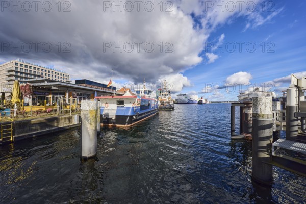 Kiel Fjord, harbor, duckdalben, quay, passenger ship, tugboat, ferry ship, ships, general architecture, outdoor area of a restaurant, bar and café Blauer Engel, water surface with small waves, blue sky, cumulus clouds, stratocumulus clouds, white and dark clouds, Kiel, state capital, district-free city, Schleswig-Holstein, Germany