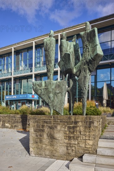Bronze sculpture The Five Continents, sculptor Bernhard Heiliger, sandstone pedestal, welcome center, modern architecture, building, glass façade, staircase, flower bed, blue sky, cumulus clouds, Stresemannplatz, Kiel, state capital, district-free city, Schleswig-Holstein, Germany