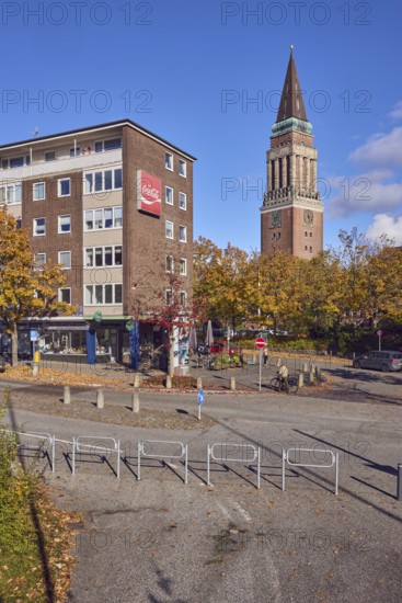 Residential and commercial buildings, brick buildings, brick architecture, general architecture, town hall tower, advertising drink Coca-Cola, barrier, central island, lantern, trees, autumn leaves, cyclists as a secondary motif, blue sky, cumulus clouds, roads intersection Kleiner Kuhberg with Waisenhofstraße, Kiel, state capital, district-free city, Schleswig-Holstein, Germany