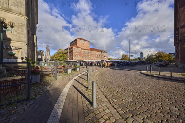 Restaurant Ratskeller, outdoor area of a restaurant, opera house, general architecture, brick building, street, barrier bollard, cobblestone road surface, square, market stalls, blue sky, cumulus clouds, Fleethörn intersection with town hall square, Kiel, state capital, district-free city, Schleswig-Holstein, Germany