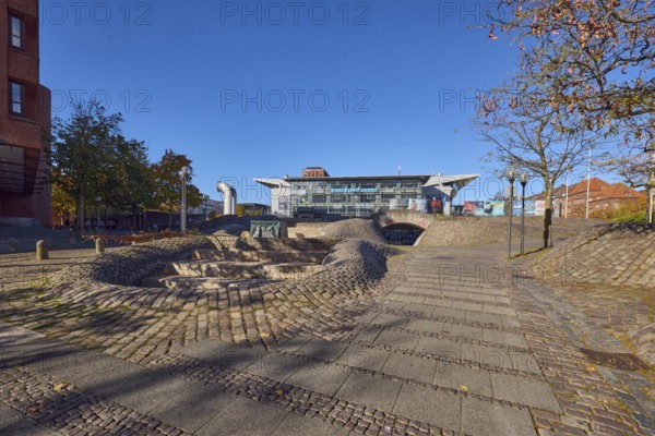 Fountain complex, multi-purpose hall Wunderino Arena or former Baltic Sea Hall, pedestrian zone, lantern, barrier bollard, footpath made of paving stones and cobblestones, trees, blue sky, cloudless, splash, Europaplatz, Kiel, state capital, district-free city, Schleswig-Holstein, Germany