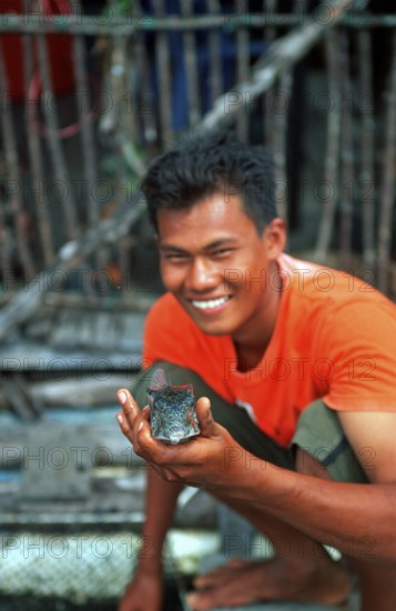 Man showing fish, fish farm in the tidal river near Krabbi, two years in front of the tsunami, Thailand, December 2002, vintage, retro, old, historic