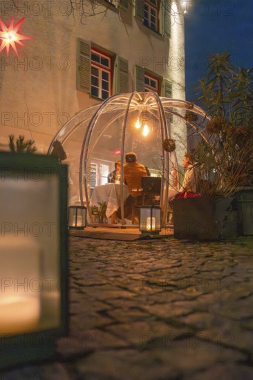 A glass dome with people illuminated at night, next to candles and on a paved path, Gastro Bubbles, Sindelfingen, Germany