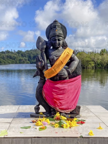 Statue sculpture of war deity Muruga, son of Shiva and Parvati, also worshipped as god of Tamil Kadavul, symbolizes courage wisdom and victory over evil, stands in holy Hindu lake Ganga Talao at religious site largest Hindu shrine for religion Hinduism outside India for believers Hindu Hindus, in the background Sacred Lake Ganga Talao crater lake in crater of extinct volcano, Grand Bassin, Le Pétrin, Mauritius