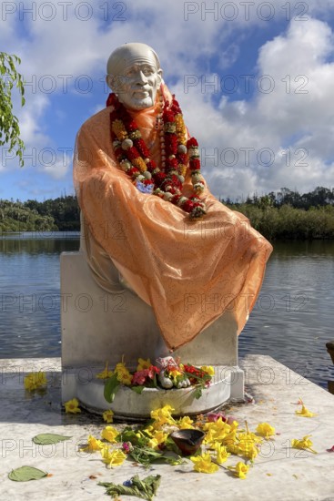 Statue of Indian spiritual master Hindu monk Shirdi Sai Baba, stands on the edge of in sacred Hindu lake Ganga Talao at religious site largest Hindu shrine for religion Hinduism outside India for devout Hindu Hindus, in the background Sacred Lake Ganga Talao crater lake in crater of extinct volcano, Grand Bassin, Le Pétrin, Mauritius