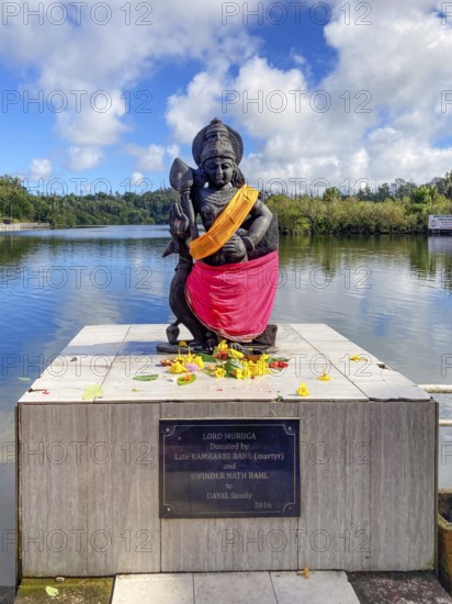 Statue sculpture of war deity Muruga, son of Shiva and Parvati, also revered as the god of the Tamil Tamil Kadavul, symbolizes courage wisdom and victory over evil, stands in holy Hindu lake Ganga Talao at religious site largest Hindu shrine for religion Hinduism outside India for believers Hindu Hindus, in the background Sacred Lake Ganga Talao crater lake in crater of extinct volcano, Grand Bassin, Le Pétrin, Mauritius