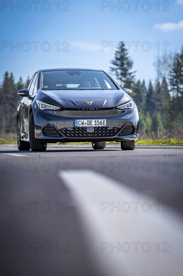 Modern black car on a country road in front of a forest under a blue sky, electric car Cupra, e-car sharing, Calw, Germany
