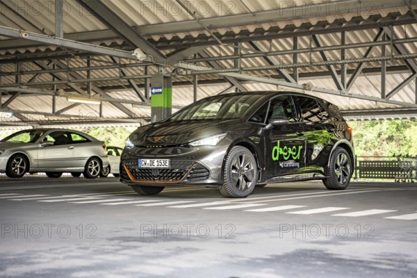 A dark car is parked under a roof in a modern parking garage, electric car Cupra, e-car sharing, Calw, Germany