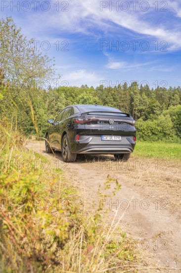A black Volkswagen on a rural path with blue sky and forest, Cupra electric car, e-car sharing, Calw, Germany