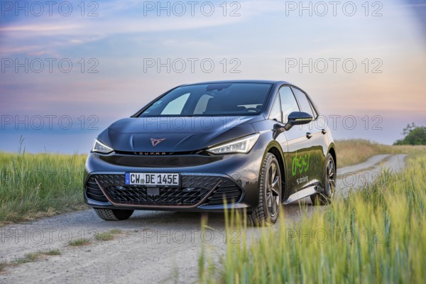 Car on a dirt road with beautiful fields and blue sky in the evening light, electric car Cupra, e-car sharing, Calw, Germany