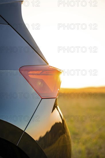 Close-up of a car light at sunset with golden evening mood in the background, electric car Cupra, e-car sharing, Calw, Germany