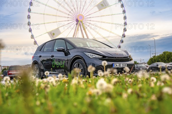 Car on a green field with a Ferris wheel in the background, electric car Cupra, e-car sharing, Calw, Germany