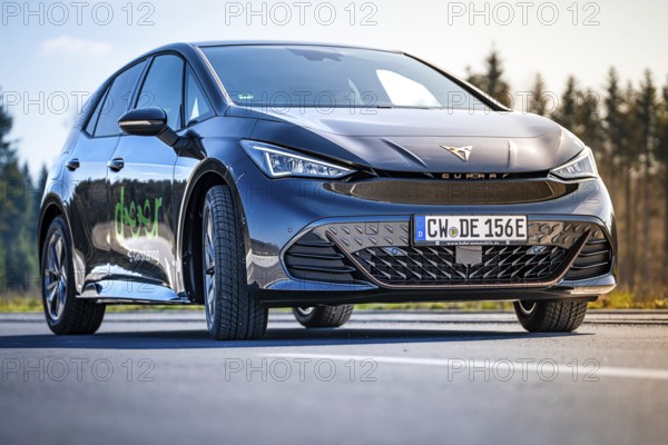 Black car on a road with forest in the background under clear sky, electric car Cupra, e-car sharing, Calw, Germany