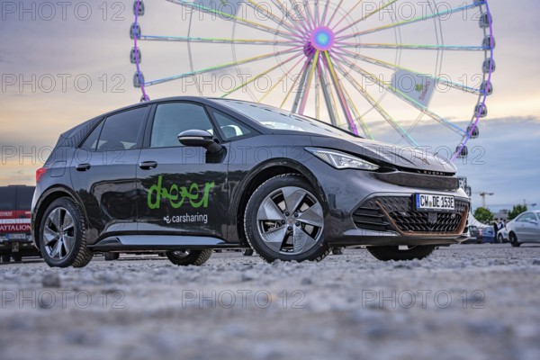 Car in front of a Ferris wheel at dusk at a fair, electric car Cupra, e-car sharing, Calw, Germany