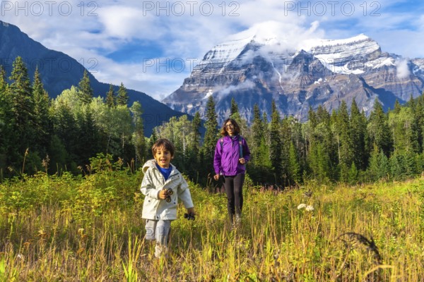 Mother and son are hiking in a meadow near mount robson, enjoying the stunning view of the canadian rockies in british columbia, canada, on a beautiful sunny day