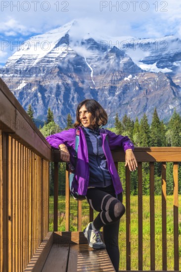 Female hiker relaxing and enjoying the majestic view of mount robson, the highest peak in the canadian rockies, british columbia, canada, during a sunny day