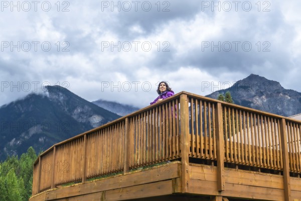 Tourist is standing on a wooden viewpoint, embracing the majestic scenery of mount robson in the canadian rockies, british columbia, with clouds adding a touch of drama to the landscape