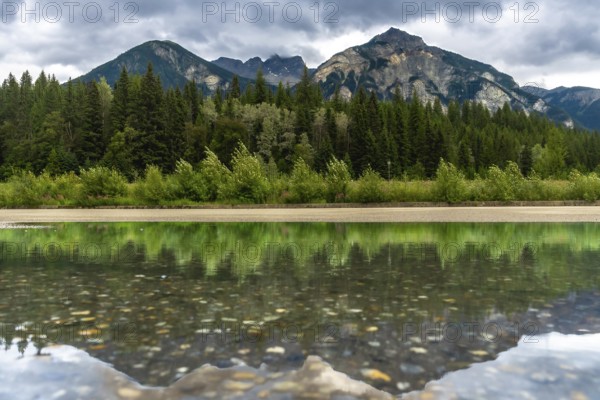 Calm waters reflecting the lush forest and majestic mount robson under a cloudy sky create a serene atmosphere in mount robson provincial park, british columbia, canada