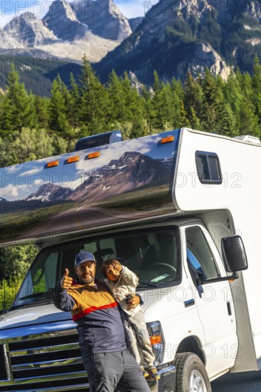 Father and son giving thumbs up in front of their rv, enjoying breathtaking views of mount robson in the canadian rockies during a memorable family road trip