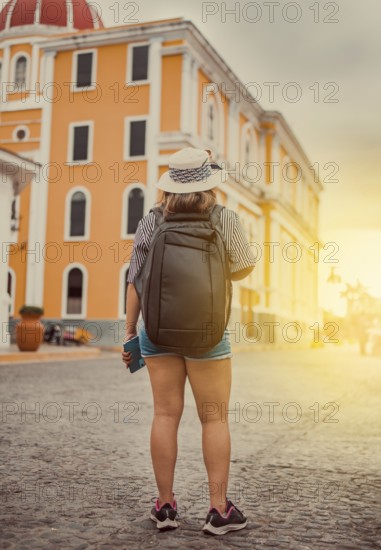 Travel woman in a tourist square at sunset, Granada, Nicaragua. Back view of tourist girl walking in a tourist square