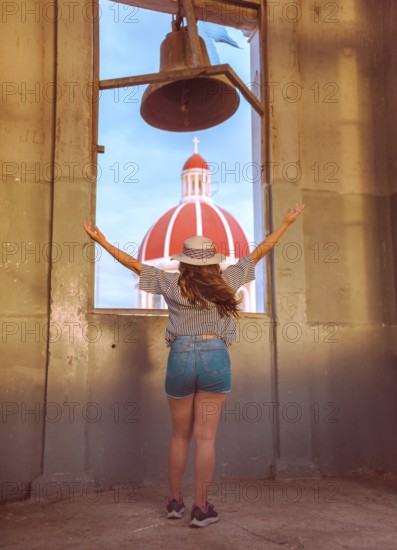 Travel woman spreading arms at viewpoint in Granada, Nicaragua Back view of tourist girl spreading arms at viewpoint at sunset
