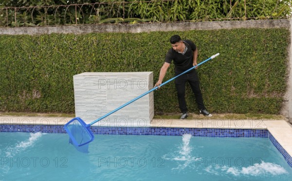 Swimming pool cleaning and maintenance concept. Maintenance person cleaning a swimming pool with skimmer, Worker cleaning a swimming pool with skimmer