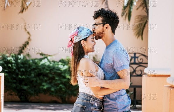 Cute couple embracing the boyfriend kisses the girl forehead. Portrait of beautiful couple in love. Boyfriend tenderly kissing his girlfriend forehead. Man kissing his girlfriend forehead outside