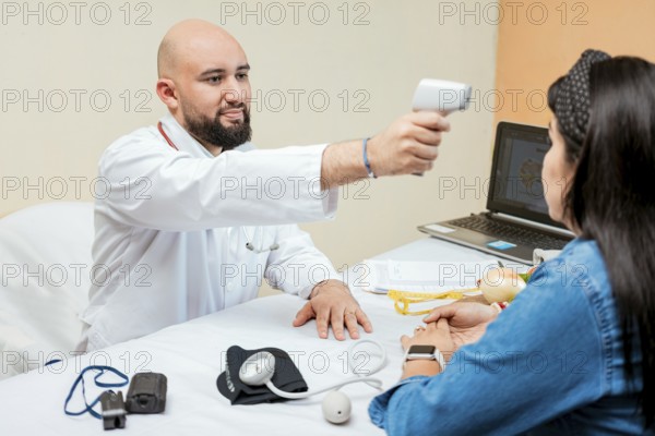 Doctor measuring temperature with infrared gun to female patient, Doctor taking temperature to woman patient in office, Male doctor taking temperature with gun to patient