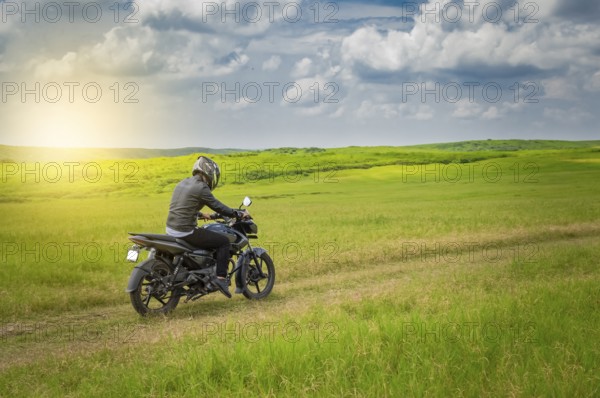 Biker man on a country road, young man on his motorcycle traveling through the countryside with copy space, man riding motorcycle in the countryside